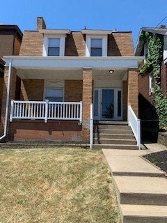 the front of a brick house with a porch and stairs